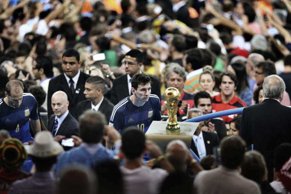 Lionel Messi devant le troph&eacute;e de la Coupe du monde